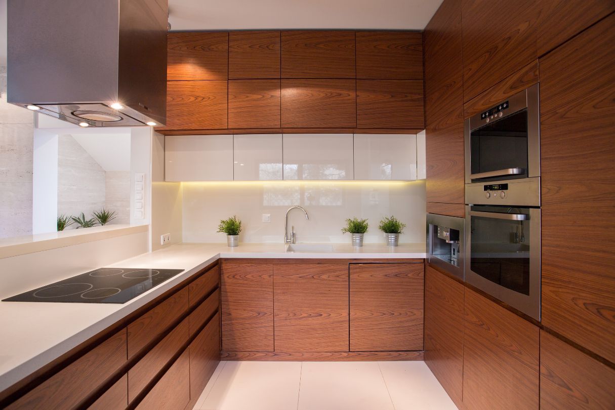 Brown custom cabinets in a small kitchen with white floors and walls.