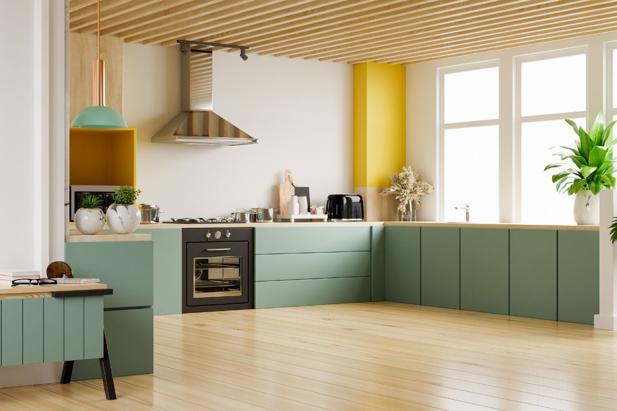 Bright kitchen with light green cabinets and wooden flooring.