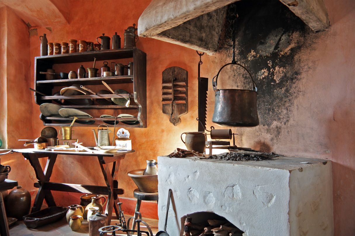 An old style kitchen with a while stove, underneath an old extraction with a small table next to it.