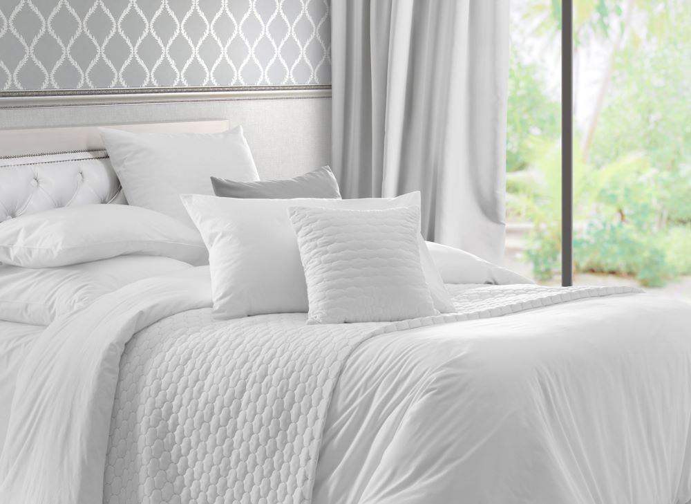 A Bed With White Sheets and Pillows in a Bedroom — Super Suds Commercial Laundry in Avoca, QLD
