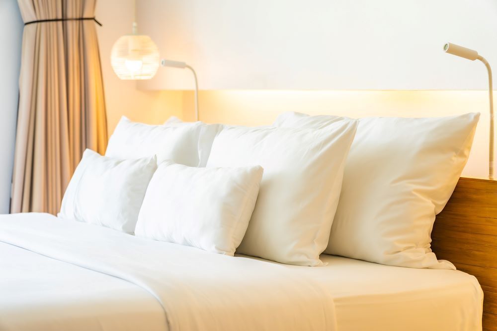 A Bed With White Sheets and Pillows in a Hotel Room — Super Suds Commercial Laundry in Avoca, QLD