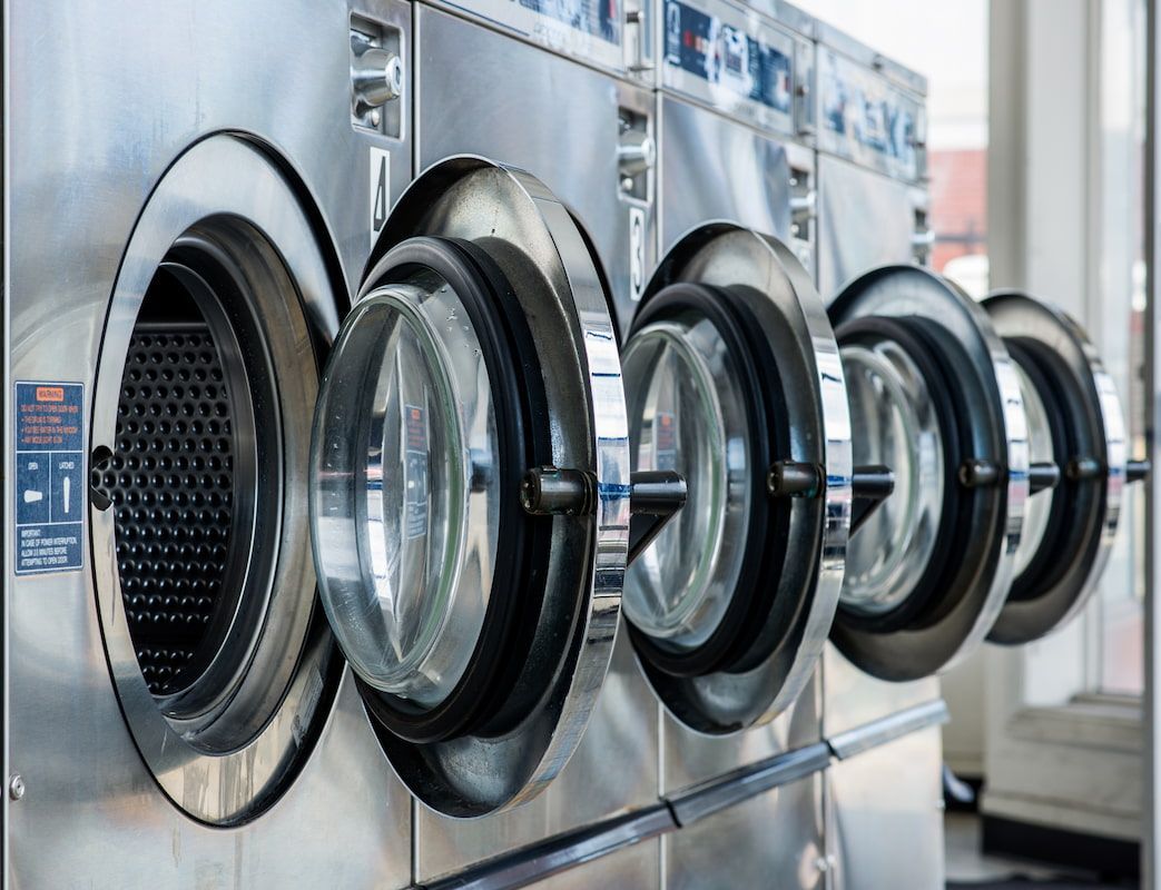 A Row of Washing Machines Are Lined up In a Laundromat — Super Suds Commercial Laundry in Avoca, QLD