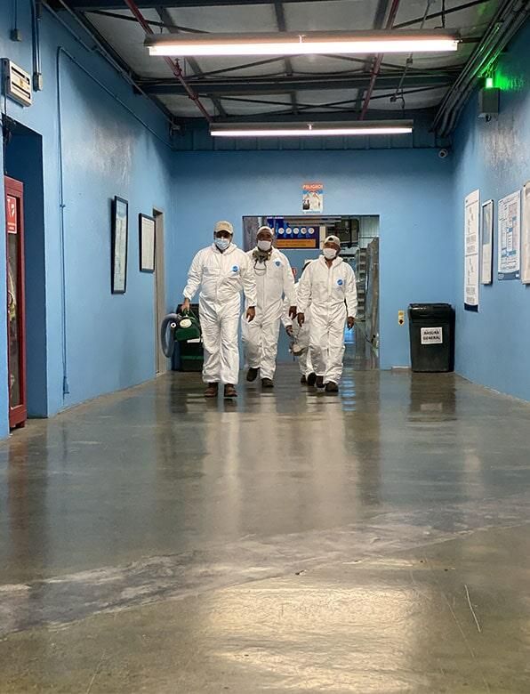 Un grupo de personas con trajes protectores camina por un pasillo.