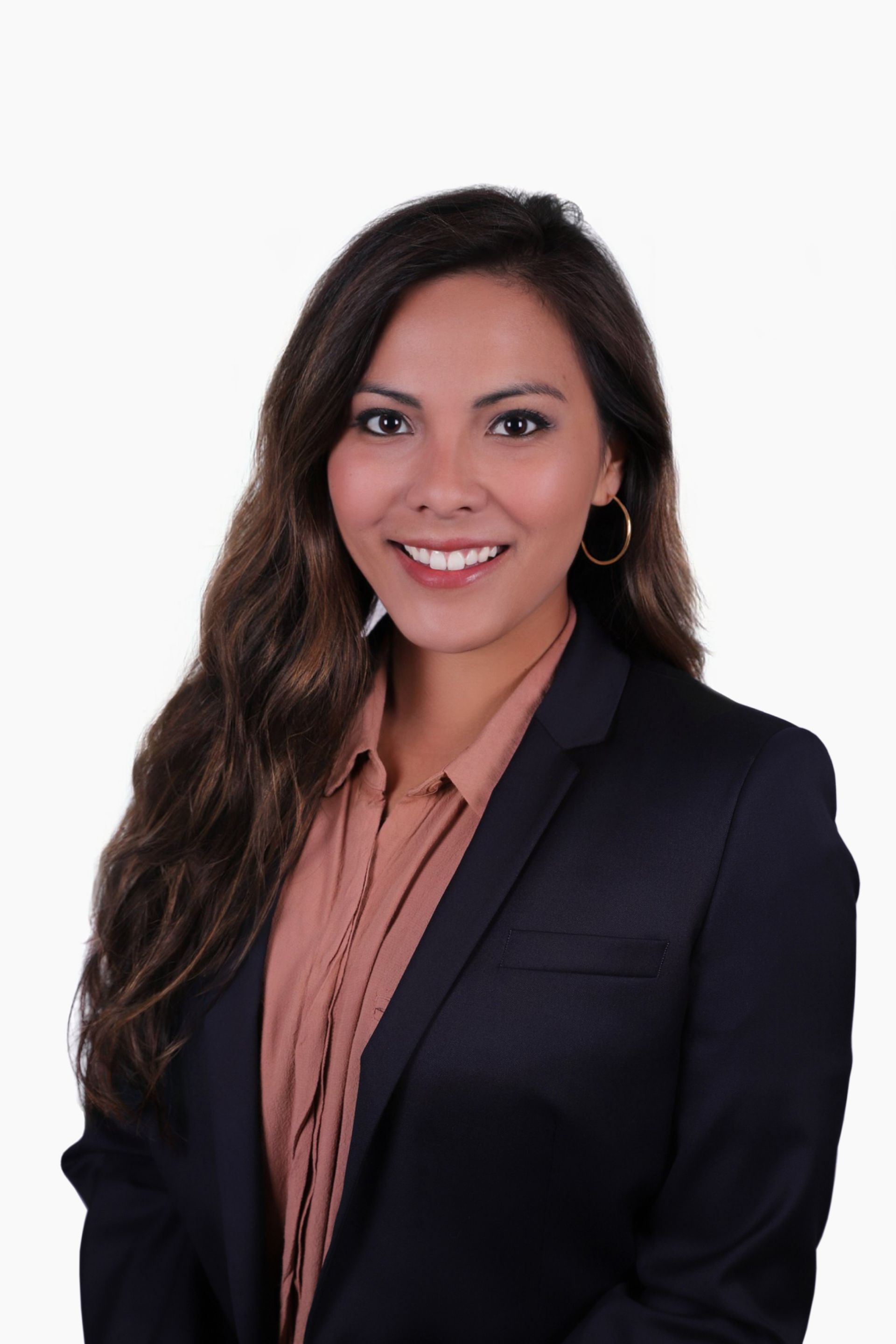 Woman wearing a dark blazer and peach-colored shirt smiles at the camera.