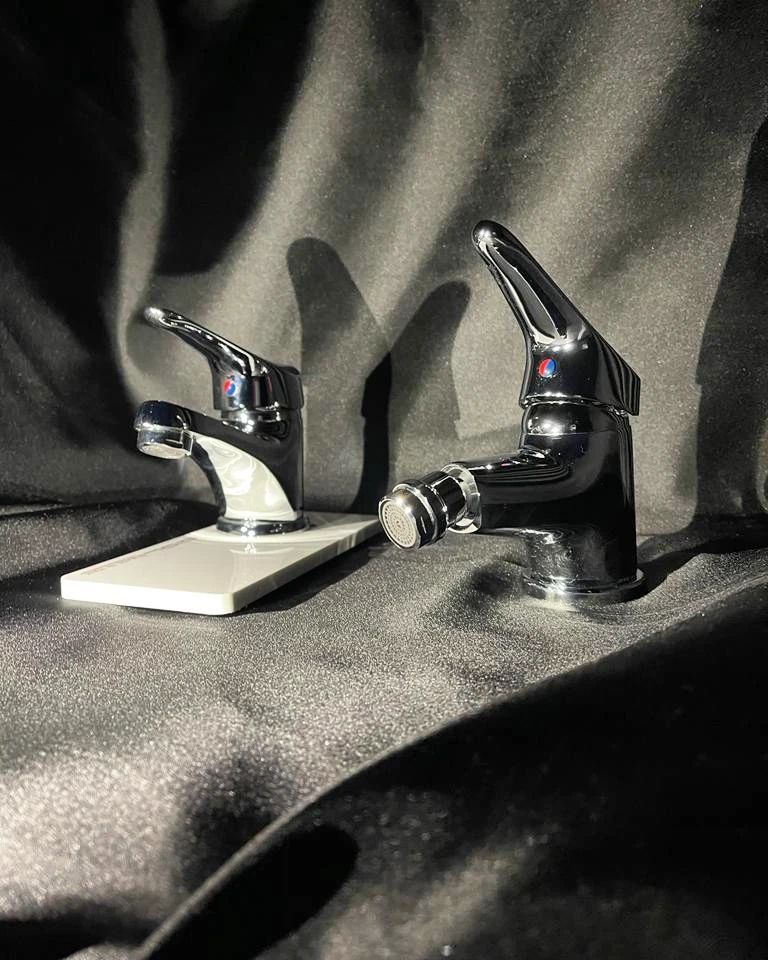 Due rubinetti cromati sono appoggiati su una superficie nera.