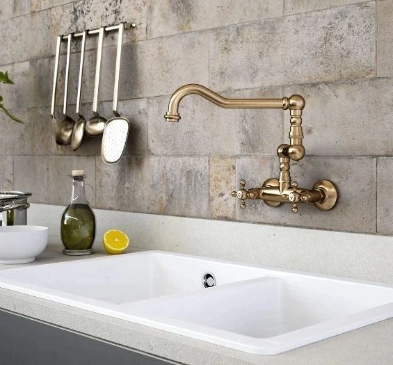 Un lavello da cucina con rubinetto in ottone e utensili appesi al muro