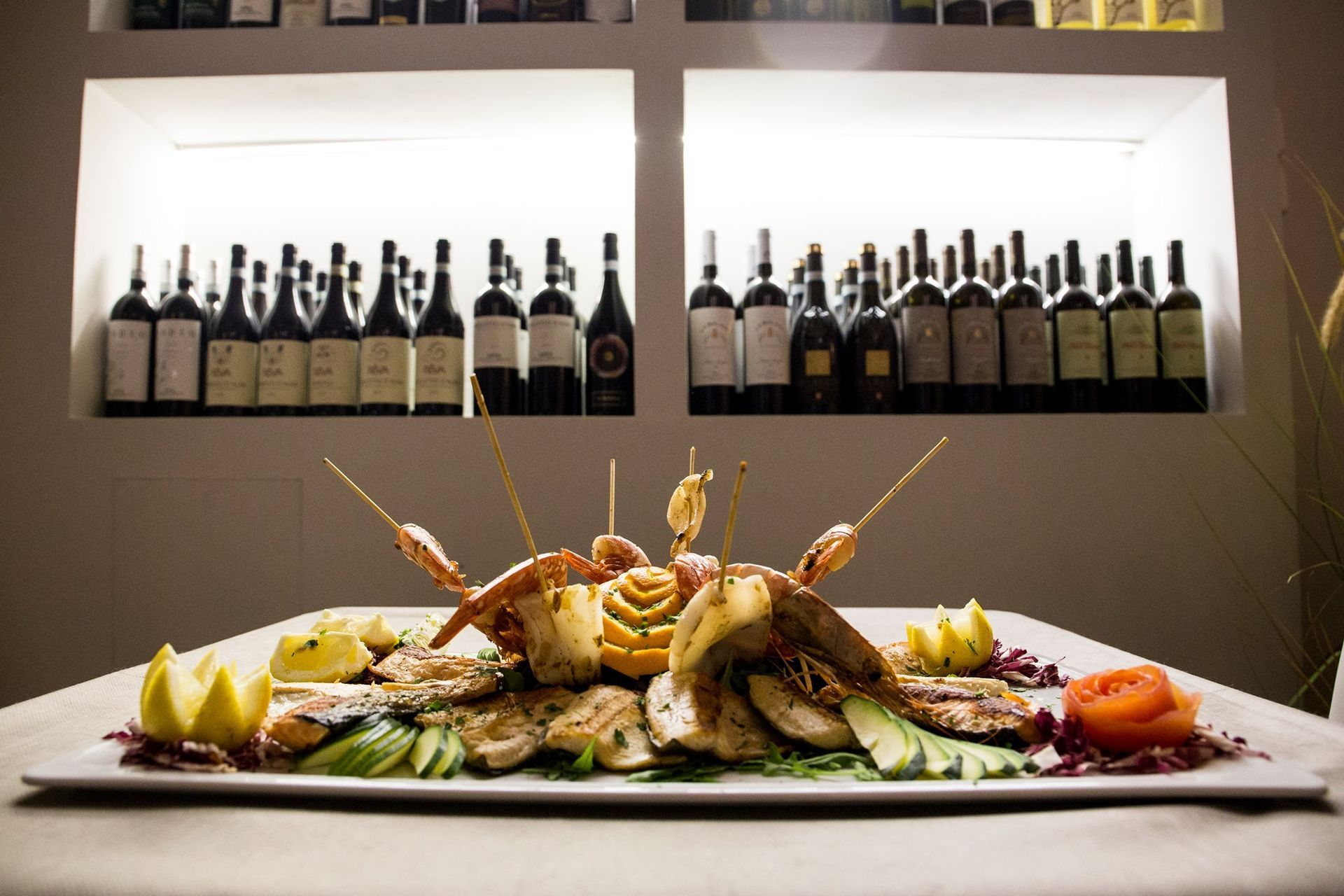 Un piatto di cibo è su un tavolo davanti a bottiglie di vino