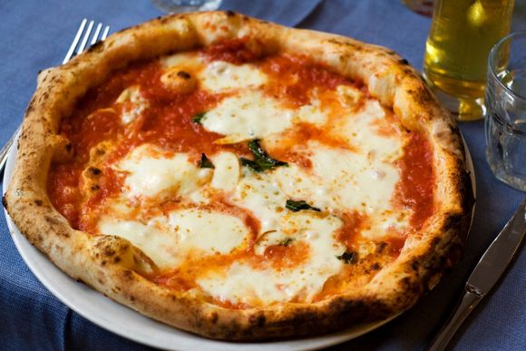 Una pizza con salsa di pomodoro e formaggio è su un piatto bianco.