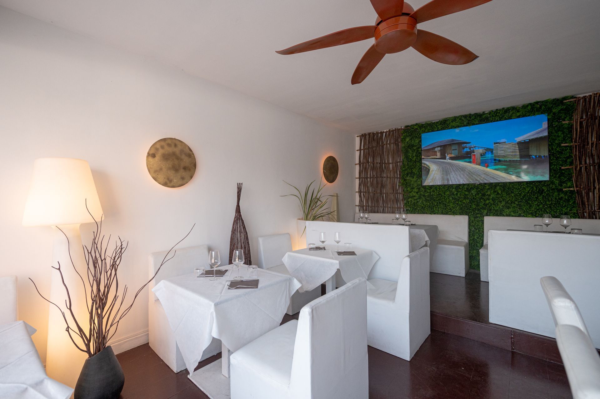 Una stanza con tavoli e sedie e un ventilatore a soffitto