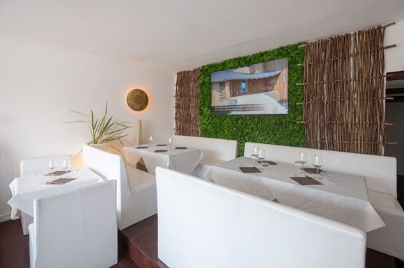 Un ristorante con tavoli e sedie bianchi e una parete verde.