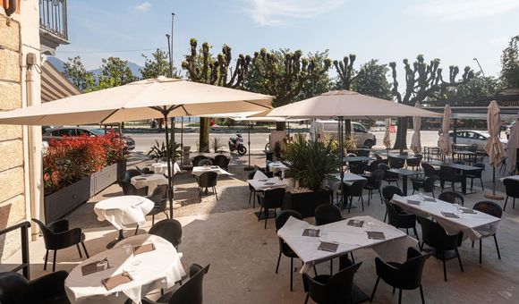 Un patio del ristorante con tavoli, sedie e ombrelloni
