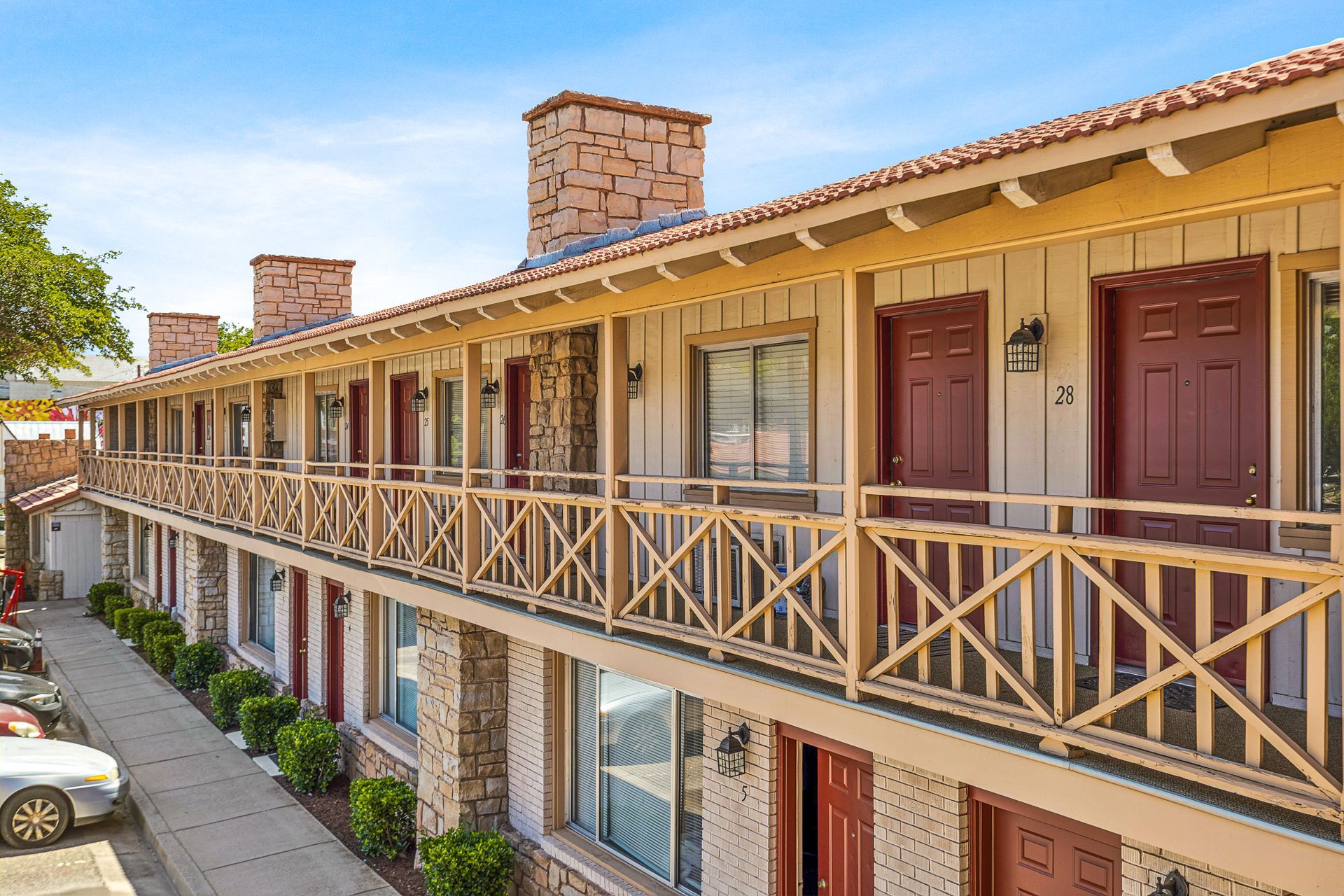 A motel with a lot of rooms and balconies and a car parked in front of it.