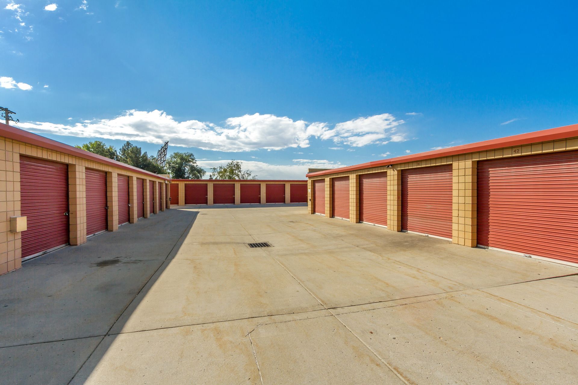 A row of red garage doors are lined up in a parking lot.