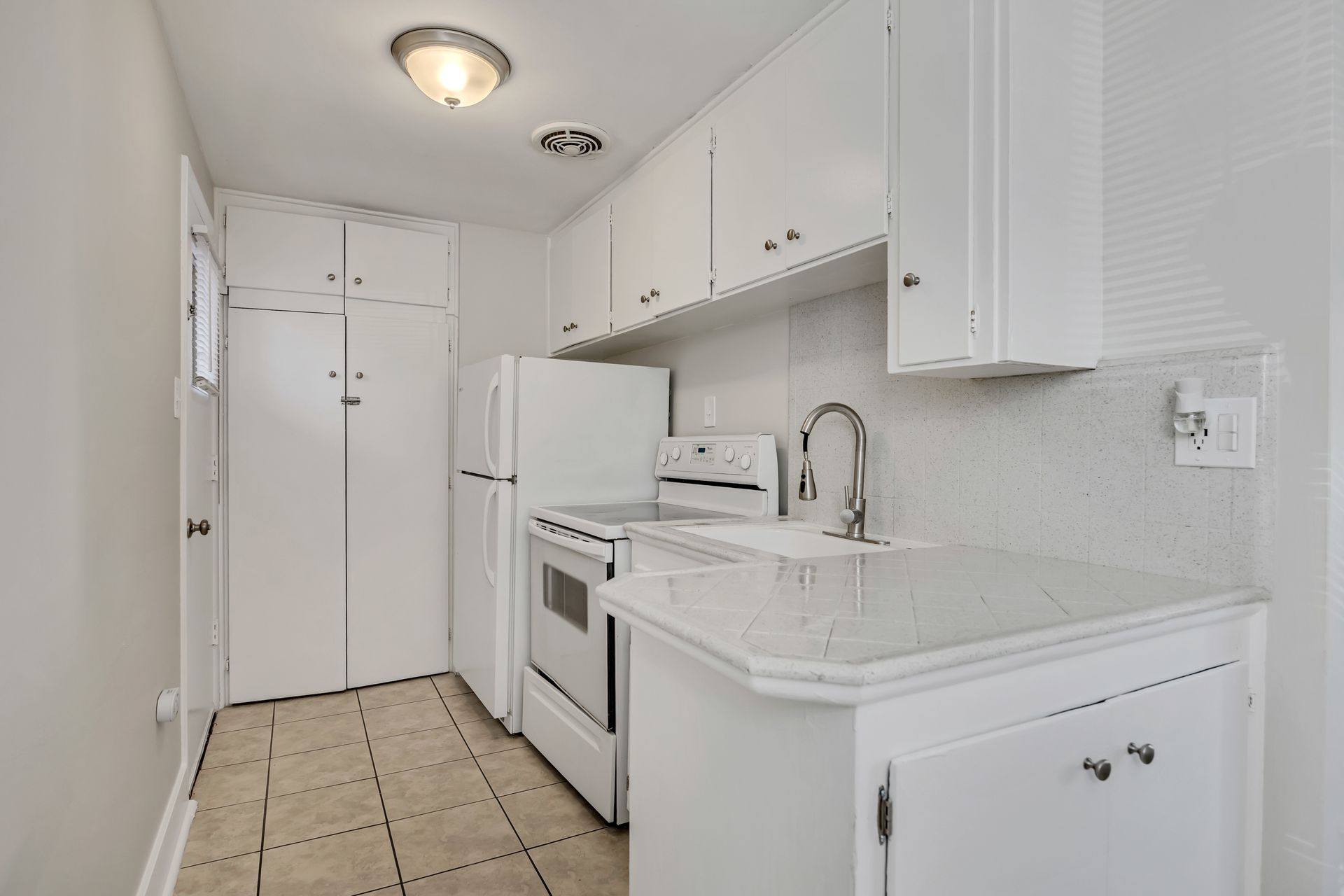 White kitchen with matching cabinets, appliances, and countertops.