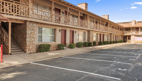 A motel with a parking lot in front of it.