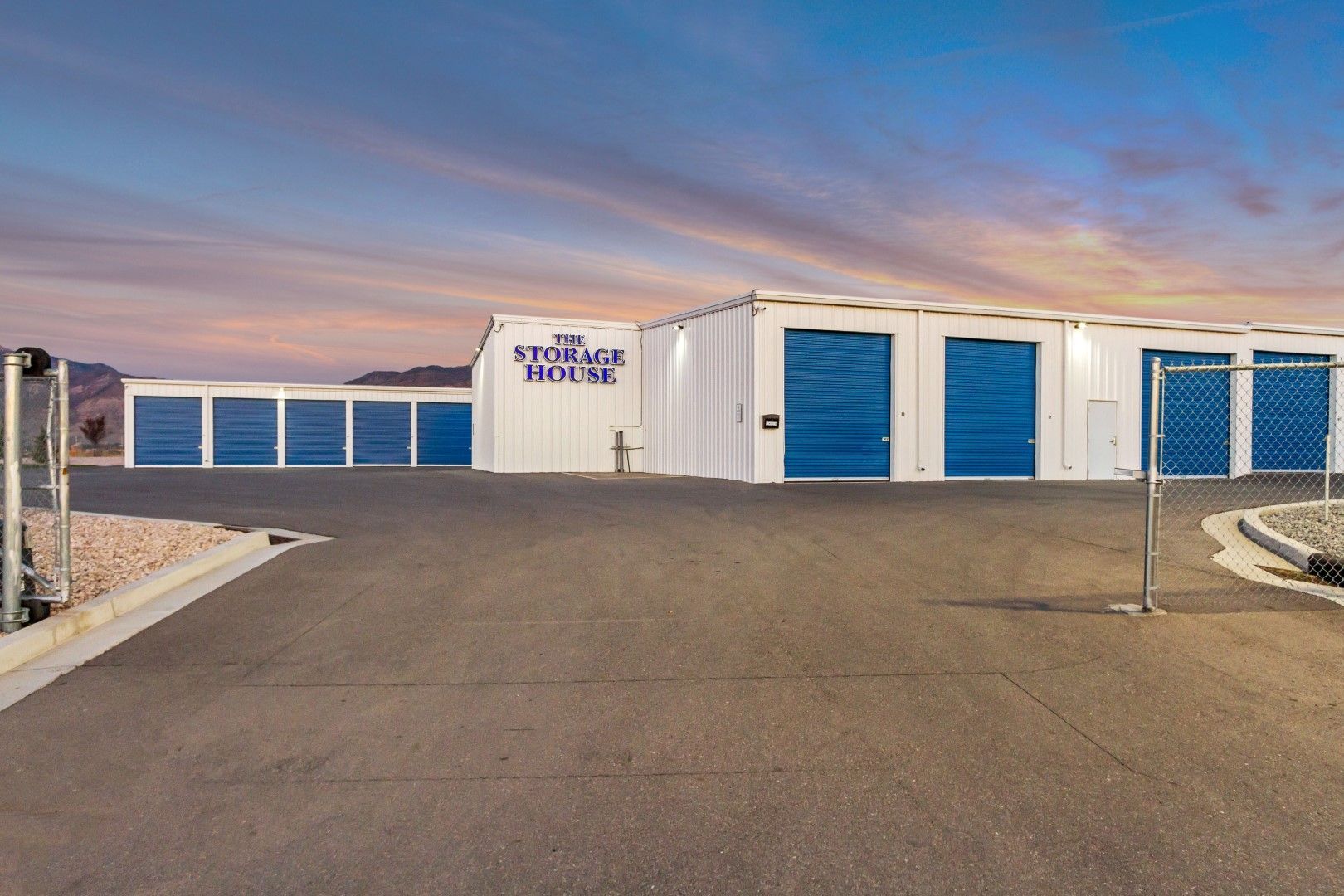 A storage facility with a lot of blue doors and a fence.