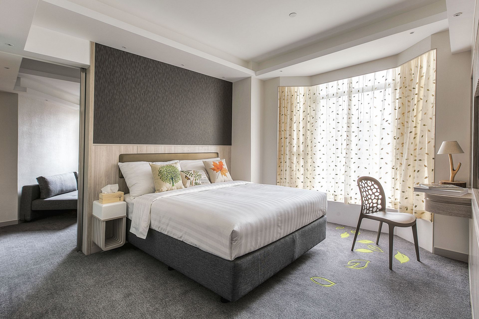 Hotel bedroom with a bed, chair, and window. Neutral colors, modern decor.