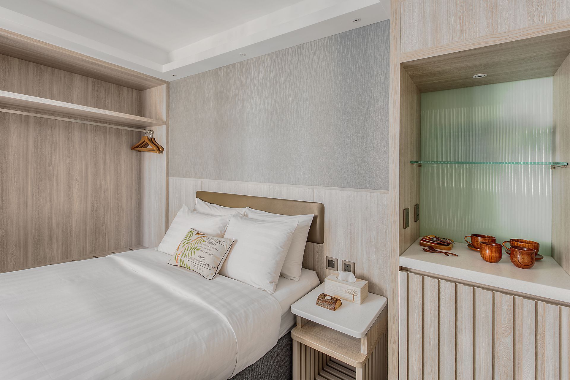 Cozy hotel bedroom with a bed, closet, nightstand, and built-in display case.