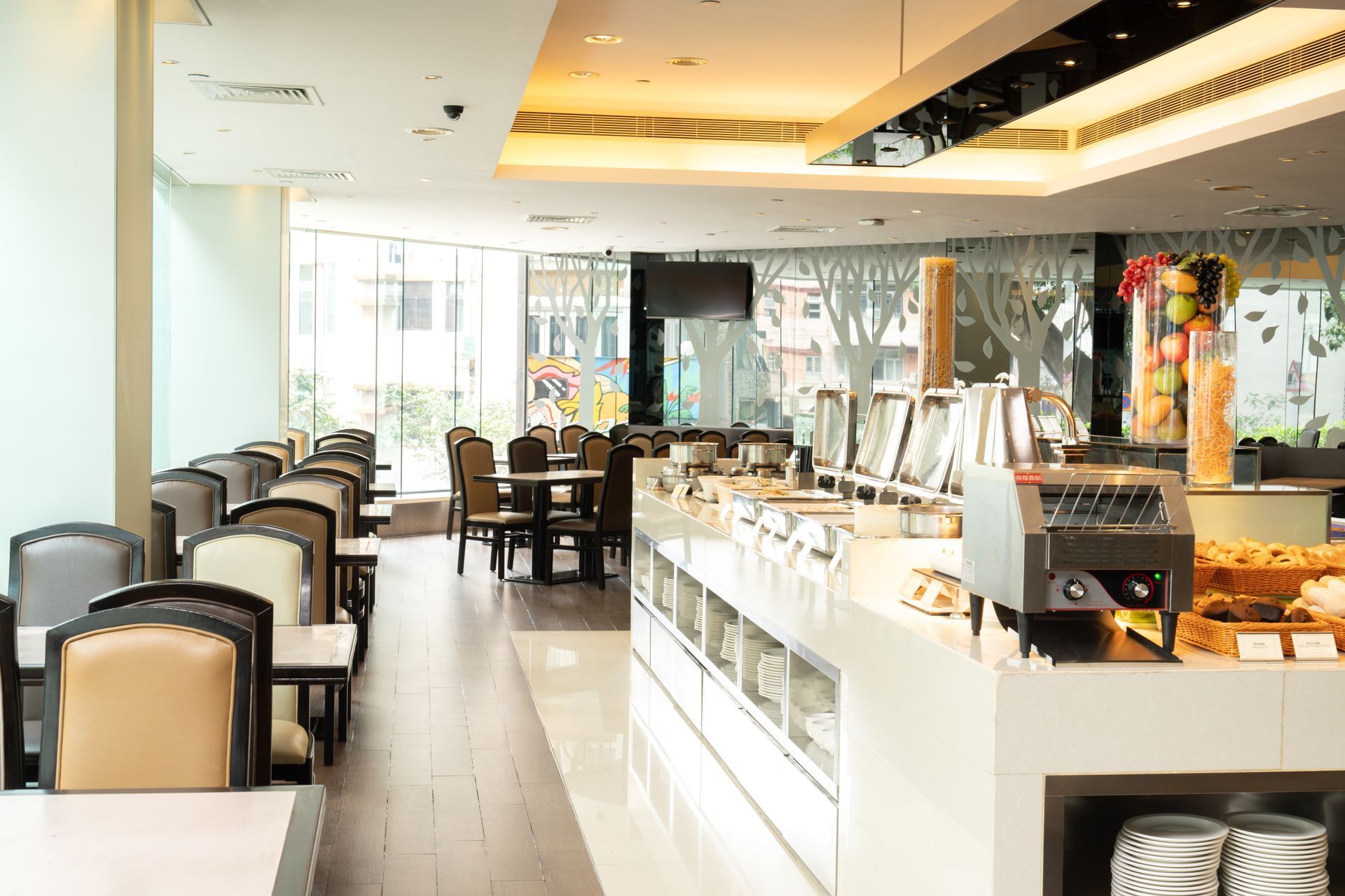 Buffet area in a modern restaurant with tables, food displays, and a large window.