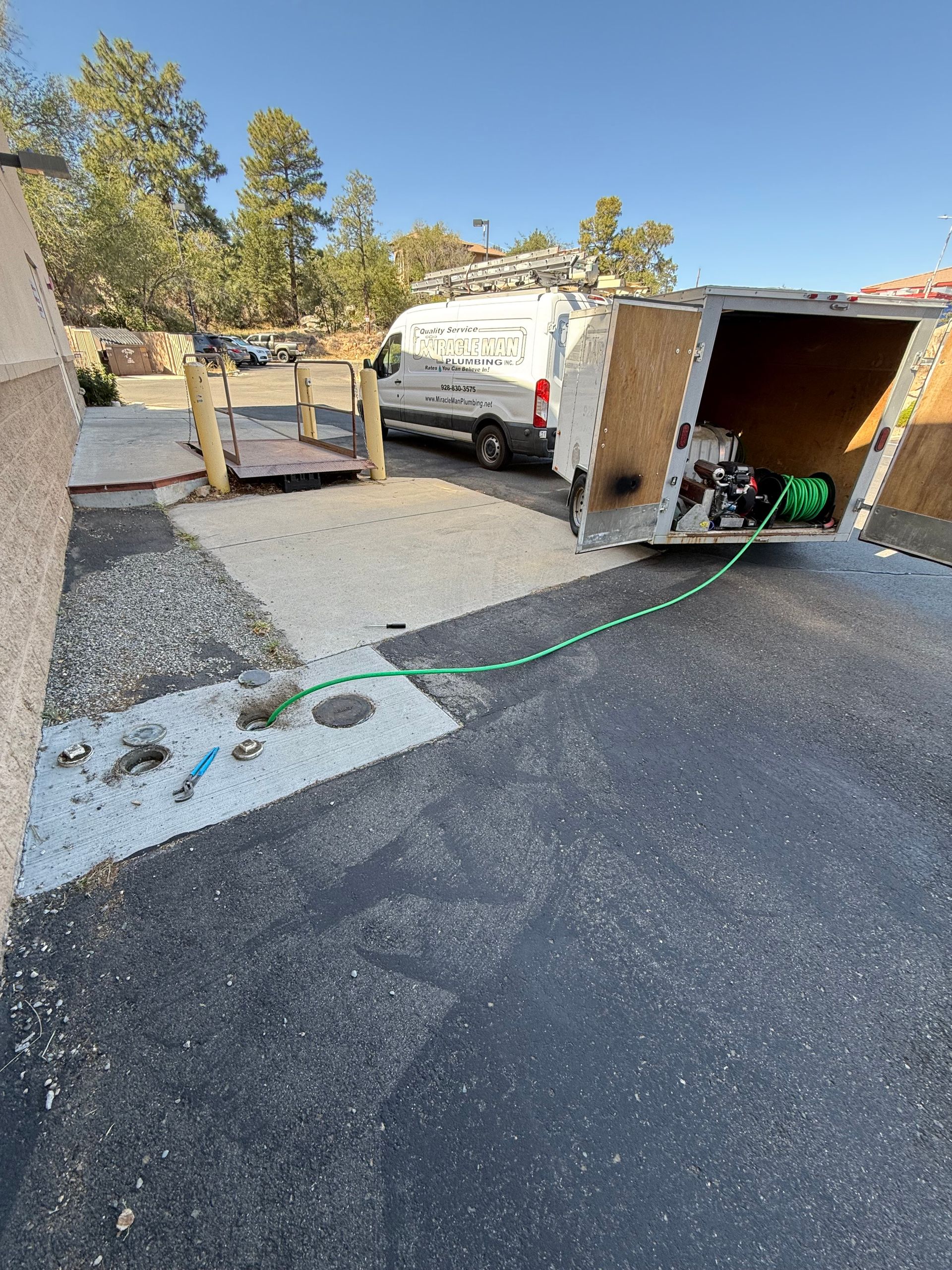 A white van with a green hose attached to it is parked on the side of the road.