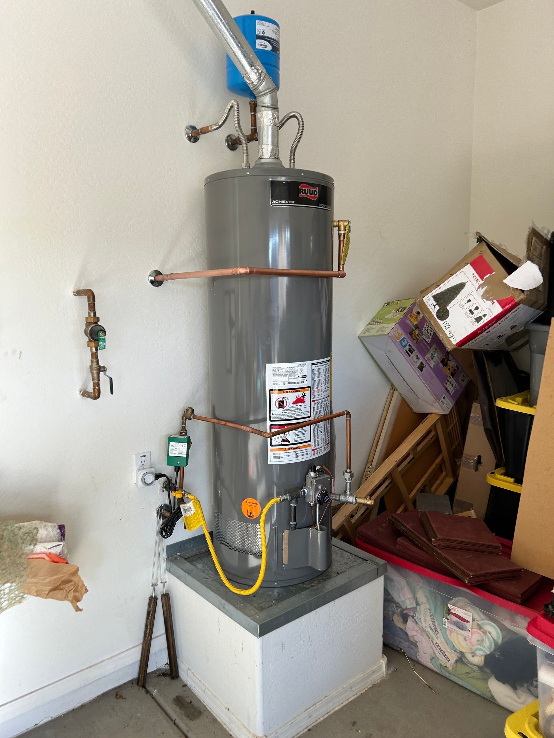 A water heater is sitting on a pedestal in a garage.