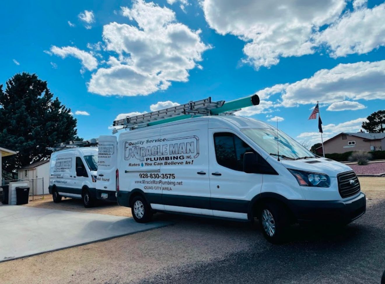 Two white vans are parked next to each other in a driveway.
