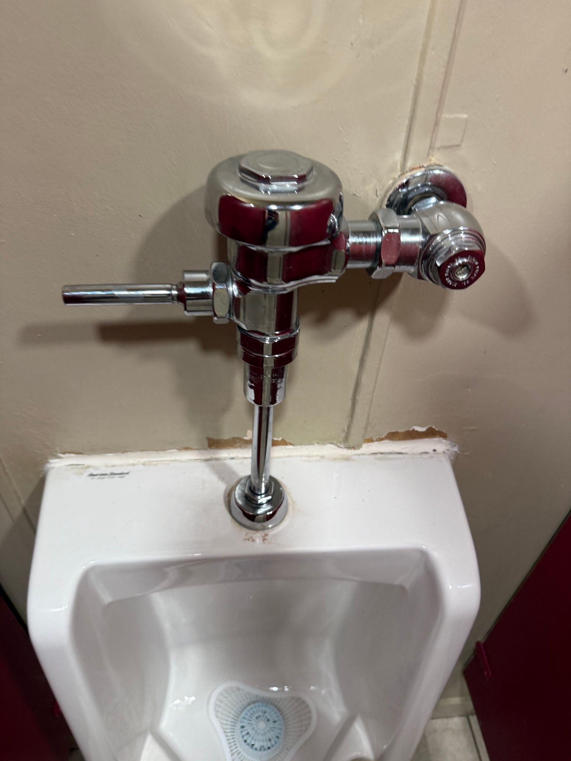 A urinal with a flush valve attached to it