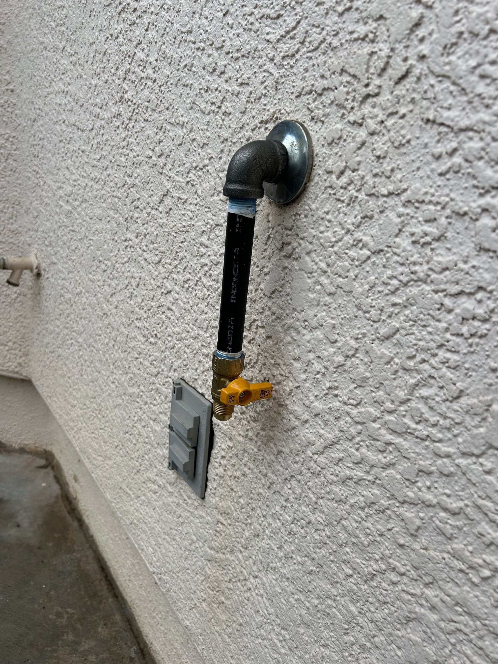 A gas pipe is attached to a white wall.