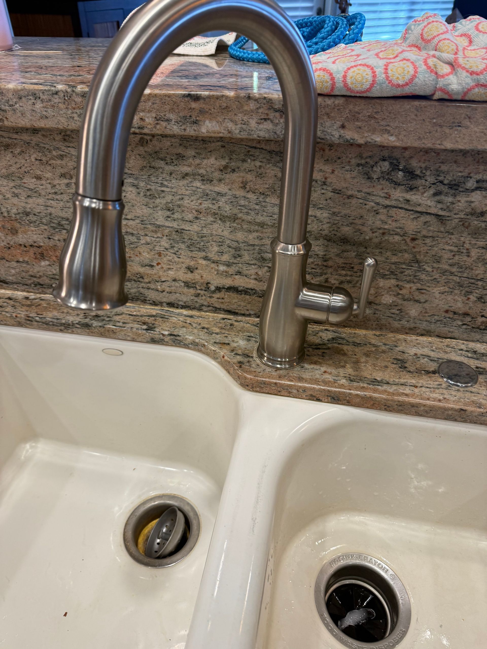 A kitchen sink with a stainless steel faucet on a granite counter top.