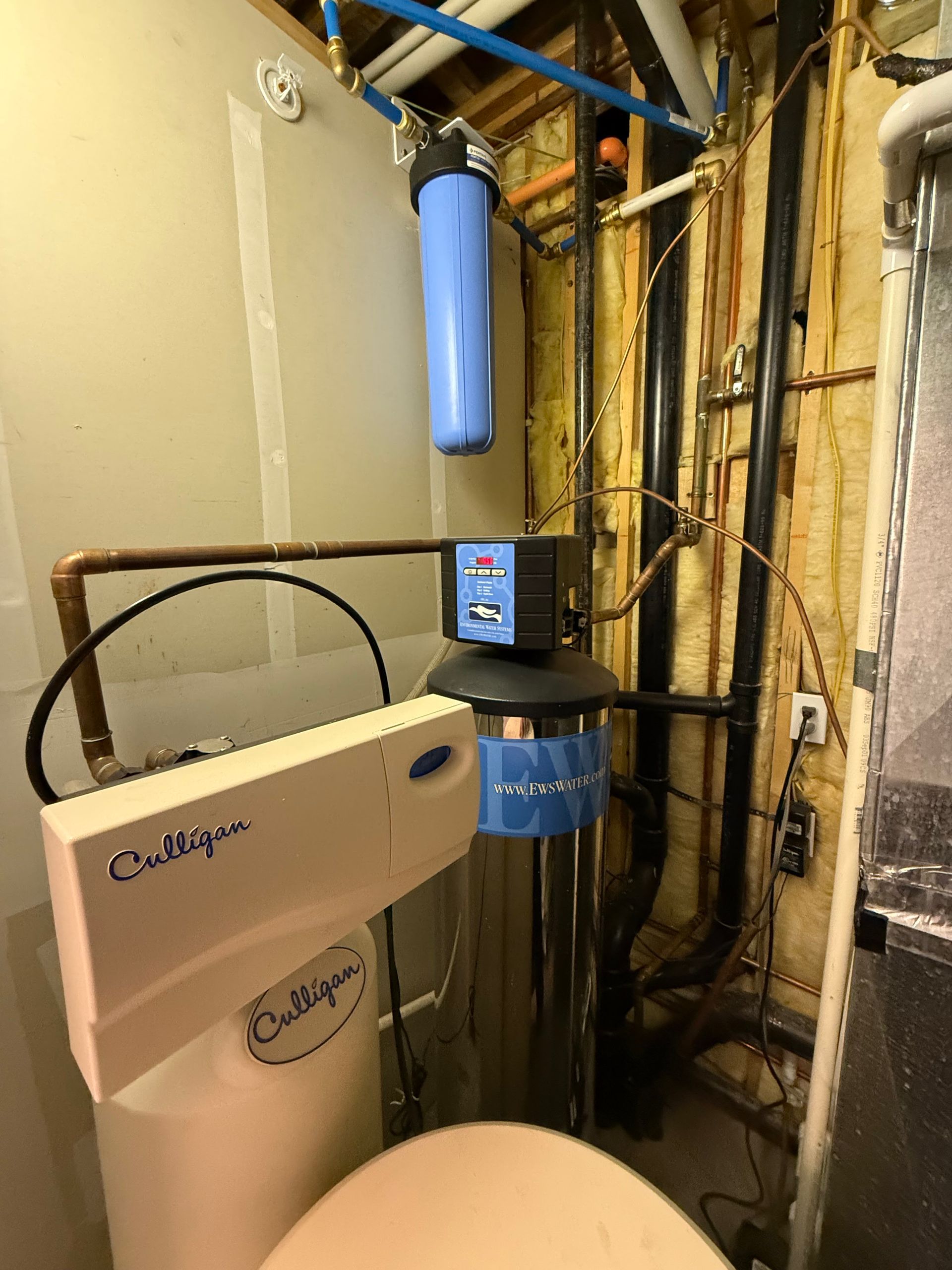 A water filter is sitting in a room next to a toilet.