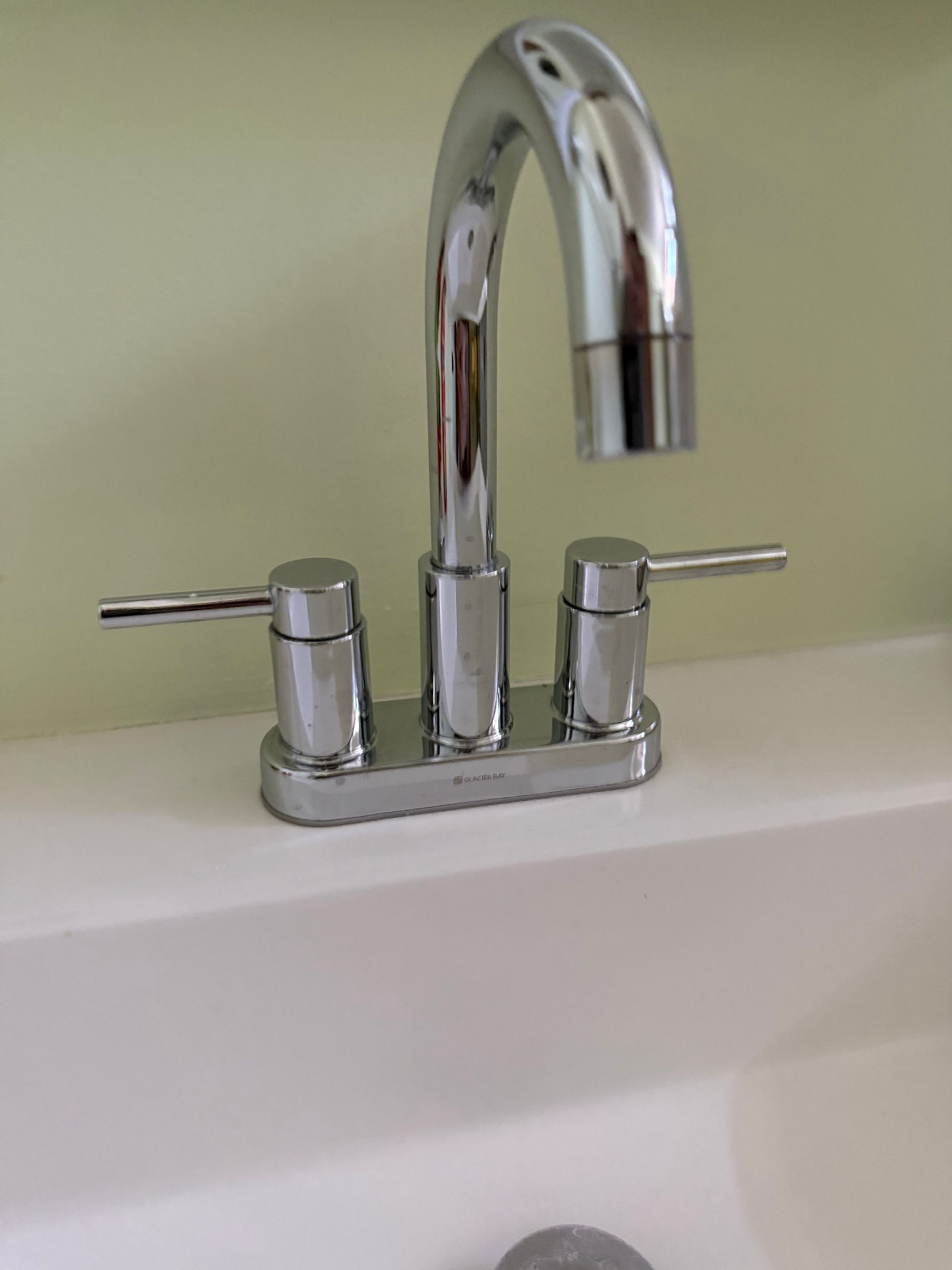 A close up of a chrome faucet on a white sink