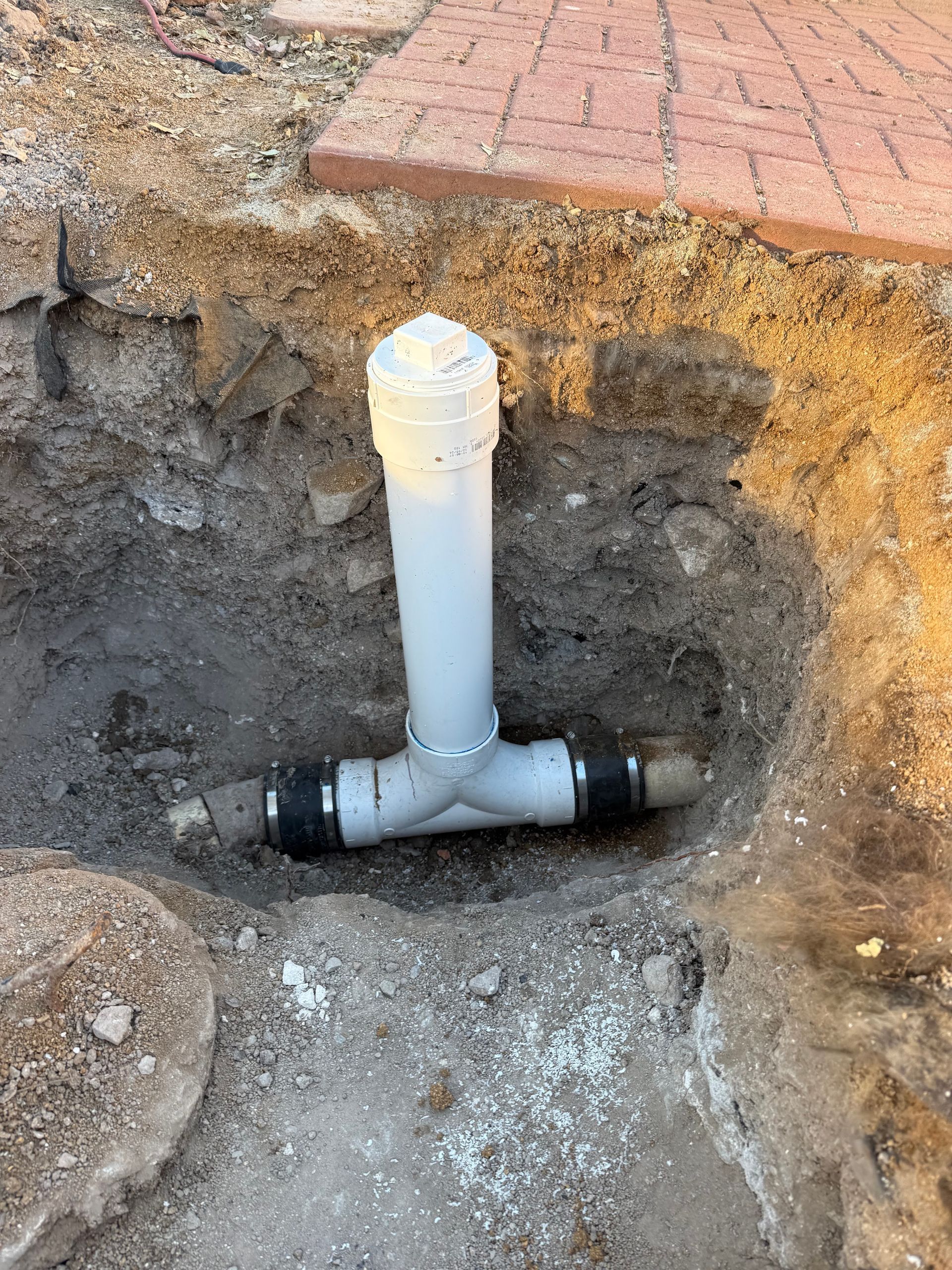A white pipe is sitting in the dirt in a hole.