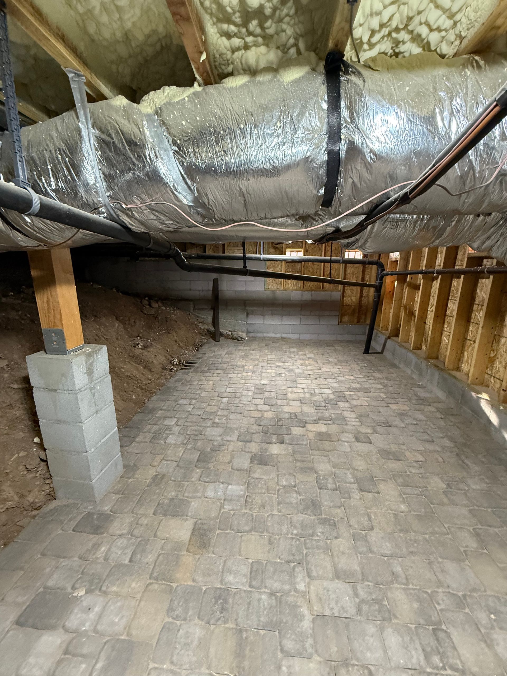A basement with a lot of pipes and insulation.