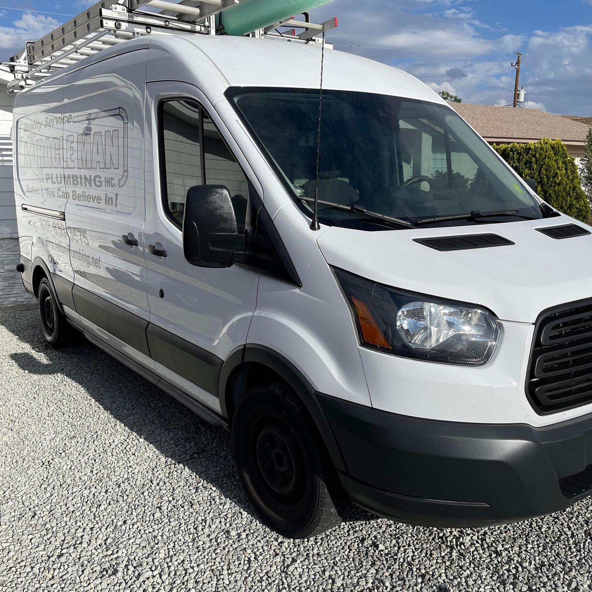 A white van is parked on gravel in front of a house