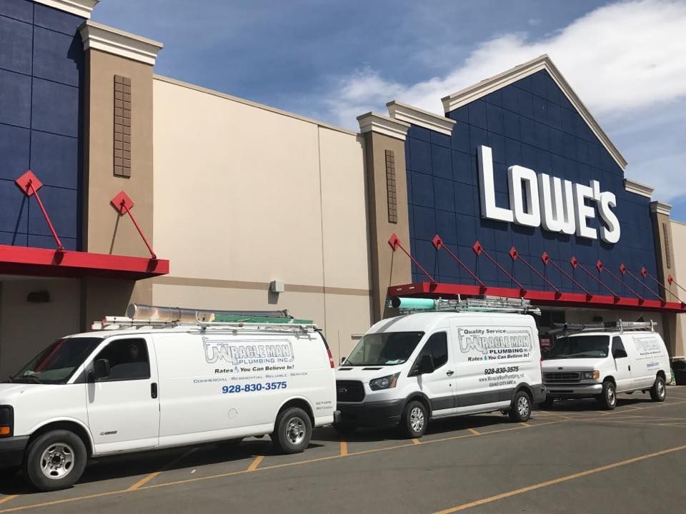 Three vans are parked in front of a lowe 's store