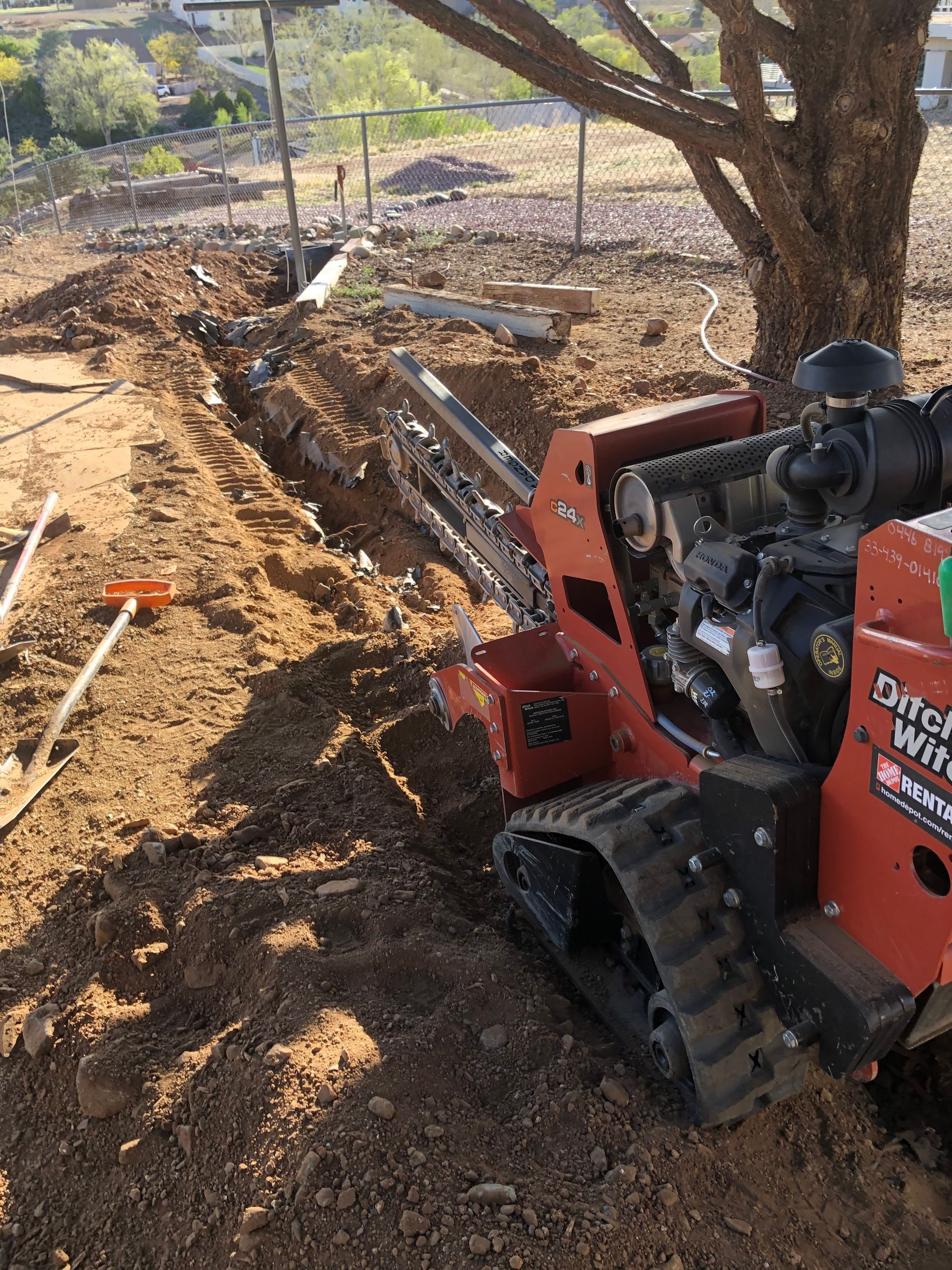 A tractor is sitting in the dirt next to a tree.
