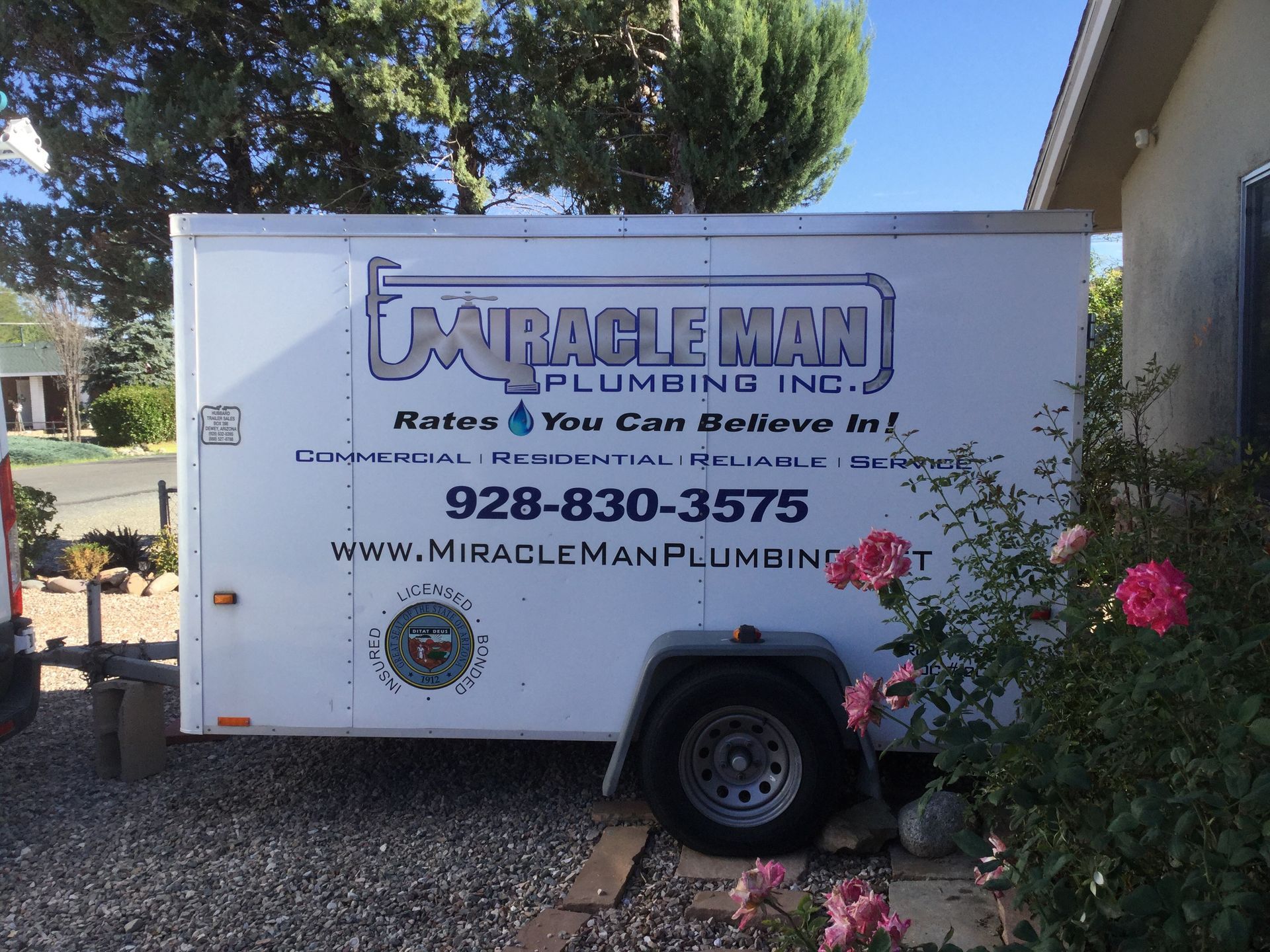 A miracle man plumbing trailer is parked in front of a house