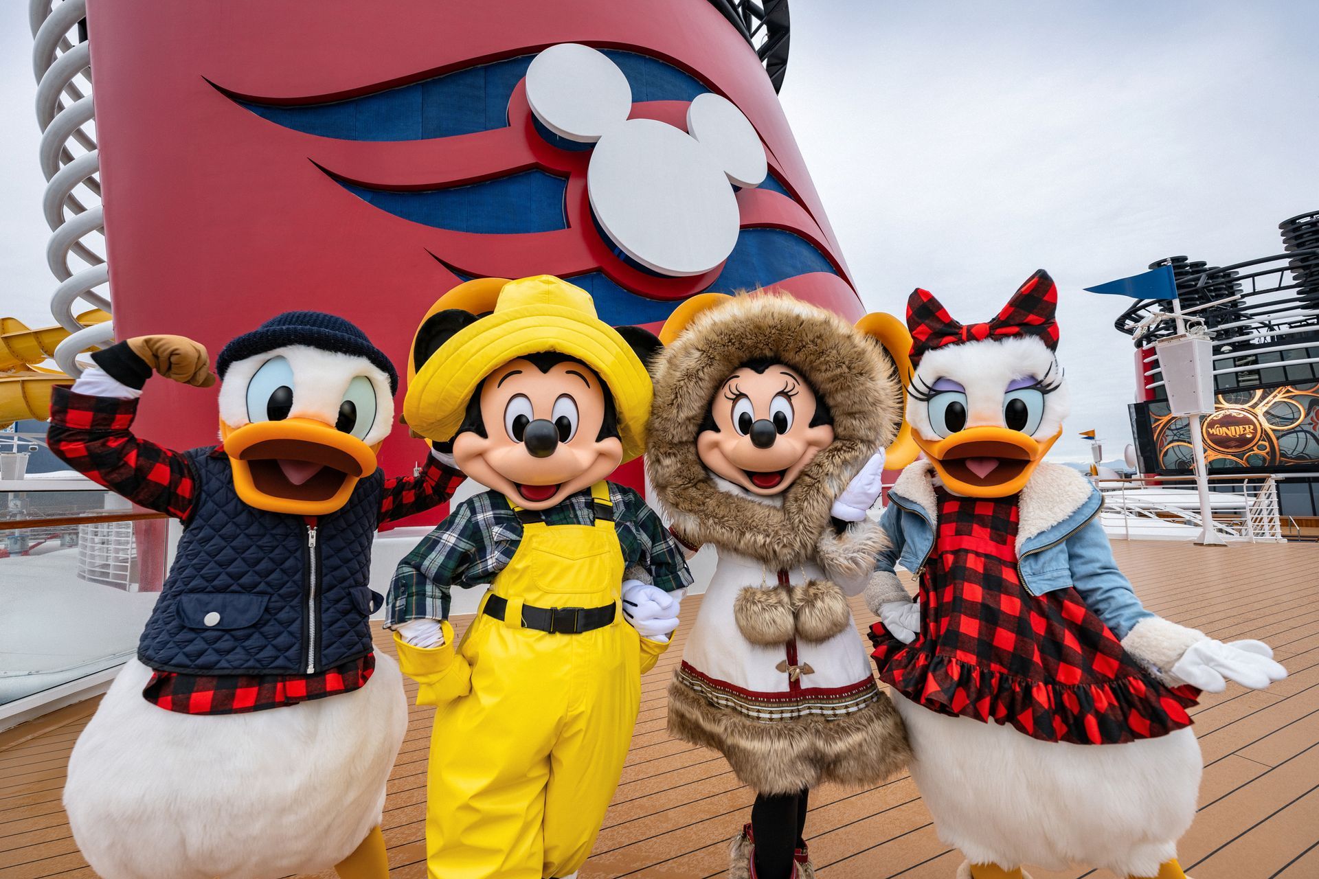 Disney characters Donald, Mickey, Minnie, and Daisy in winter attire on a cruise ship deck.