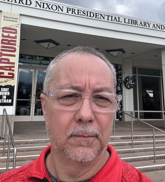 A man is taking a selfie in front of the richard nixon presidential library and museum.