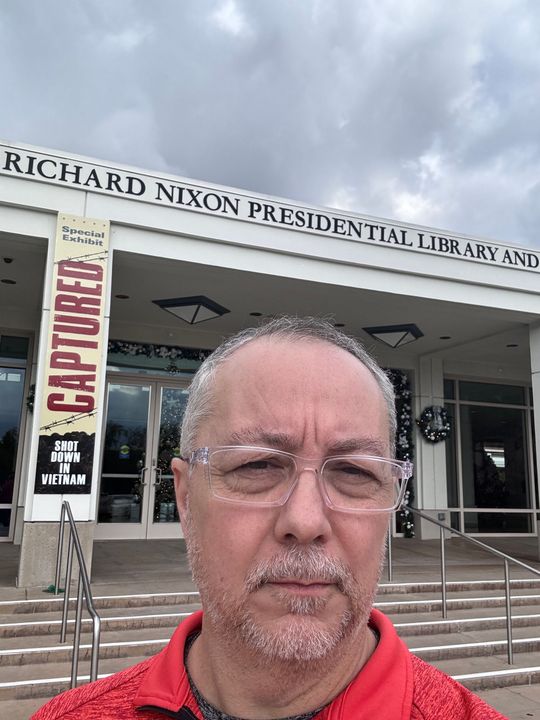 A man is taking a selfie in front of the richard nixon presidential library and museum.