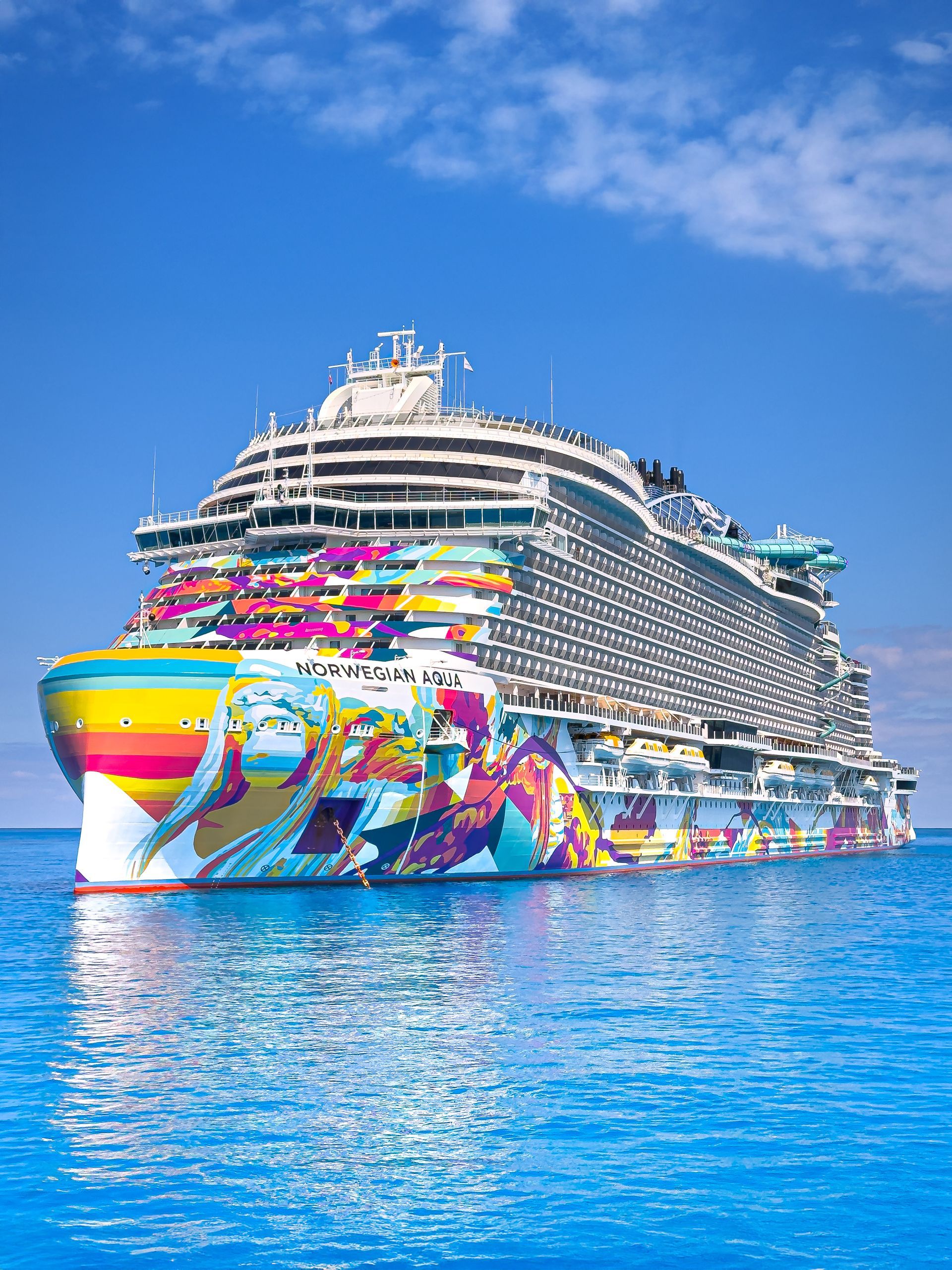 NCL cruise ship on blue water under a bright blue sky.