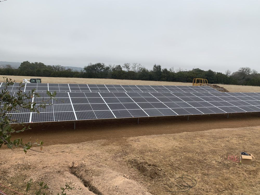 A row of solar panels sitting on top of a dirt field.