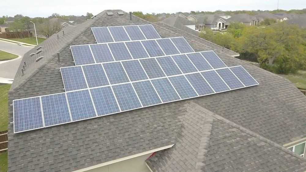 There are many solar panels on the roof of a house.
