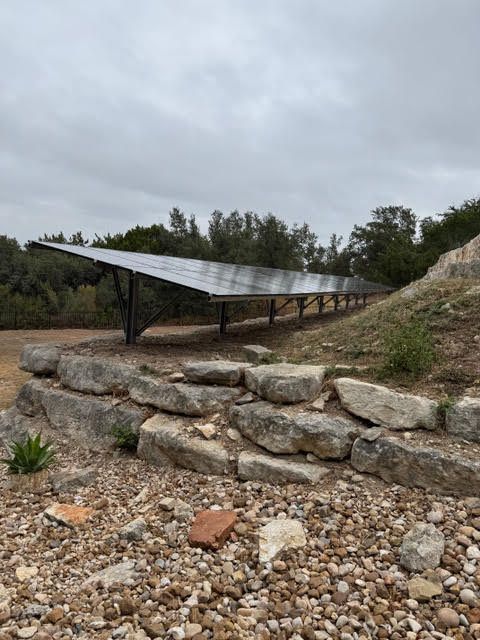 A row of solar panels are sitting on top of a rocky hillside.