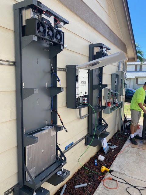 A man in a green shirt is working on a solar panel on the side of a house