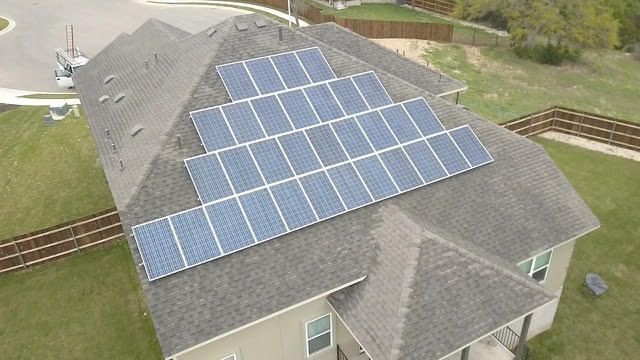 An aerial view of a house with solar panels on the roof.