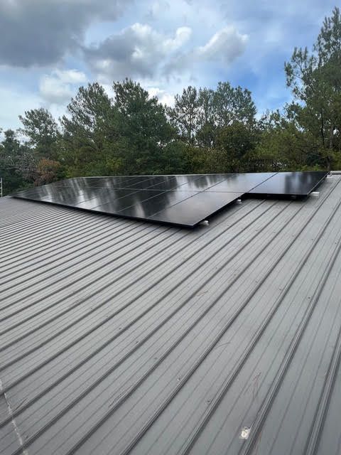A row of solar panels are sitting on top of a metal roof.