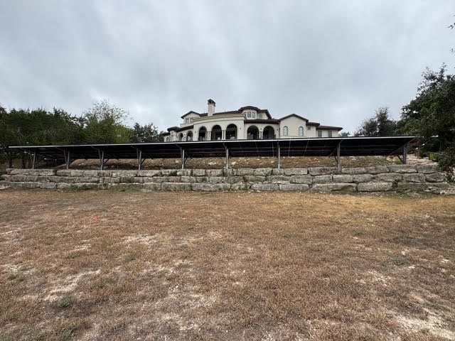 A large house is sitting on top of a dry grass field.