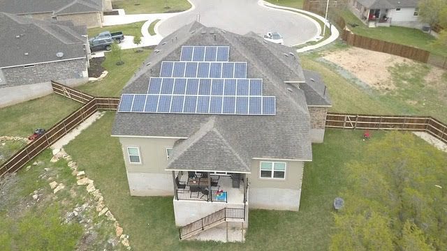 An aerial view of a house with solar panels on the roof.