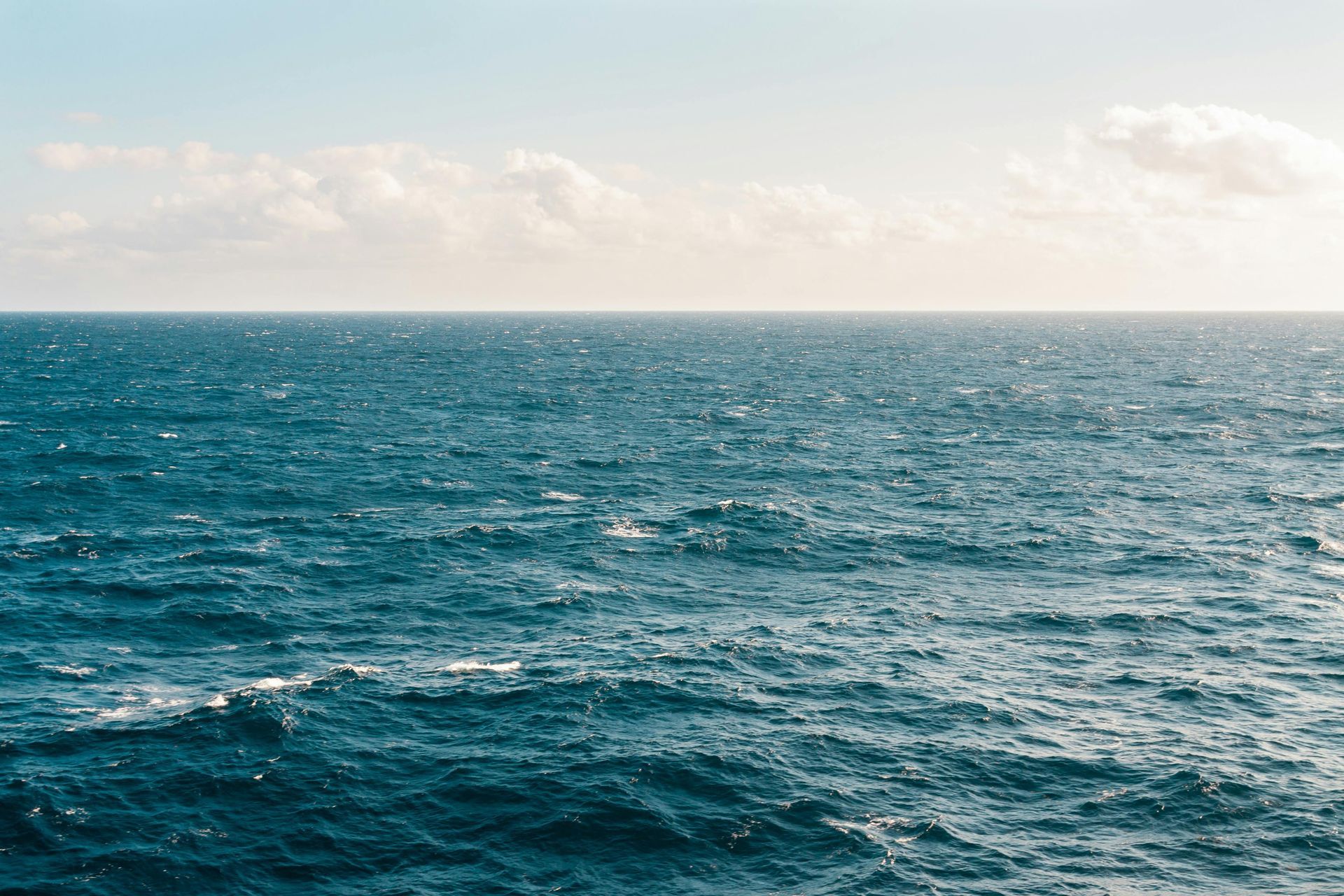 A large body of water with waves and a blue sky in the background.